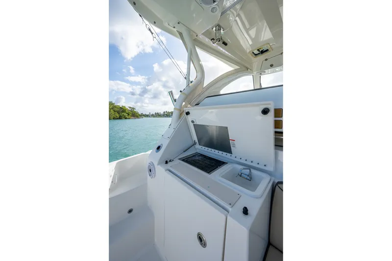 Slide: The Image of 2020 Pursuit OS 355 Offshore boat interior with sink and grill, overlooking serene water. - 33