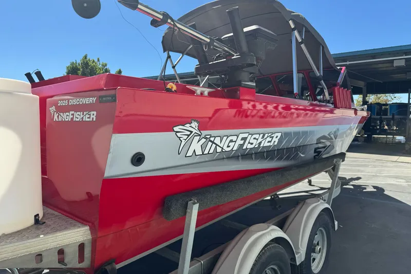 Slide: The Image of Red 2016 KingFisher 2025 Discovery boat on trailer, parked outdoors under clear sky. - 6