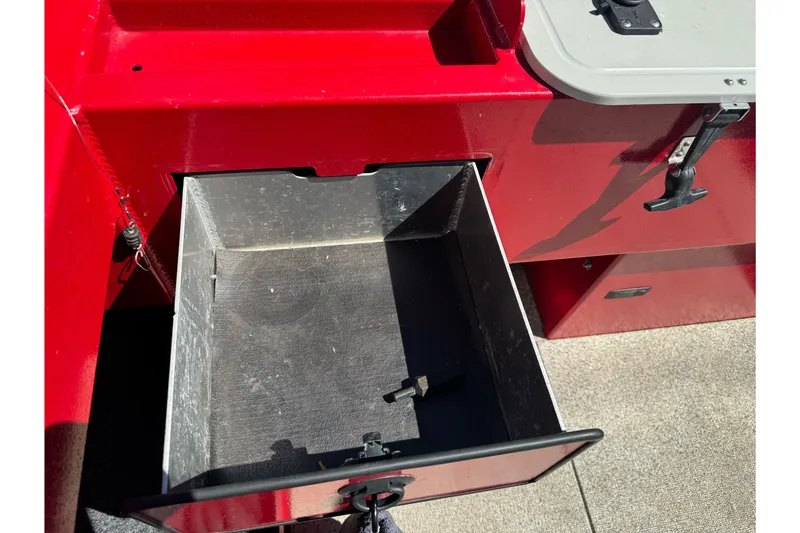 Slide: The Image of Open storage compartment in a 2016 KingFisher 2025 Discovery boat, featuring a red exterior. - 26