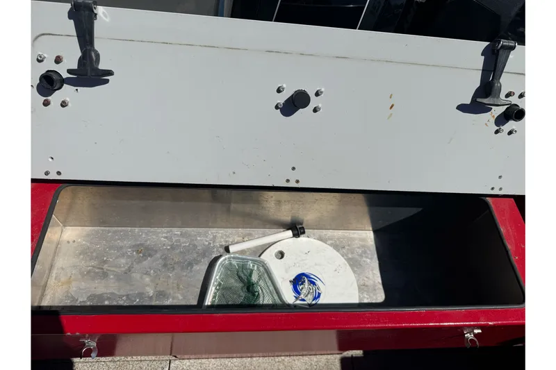 Slide: The Image of Open storage compartment on a 2016 KingFisher 2025 Discovery boat, featuring fishing gear. - 25