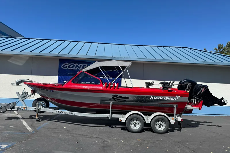 Slide: The Image of Red KingFisher 2025 Discovery boat on trailer, parked outdoors, under clear blue sky. - 0
