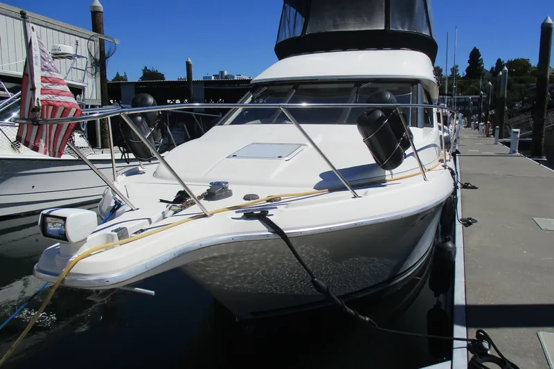 Slide: The Image of 1995 Bayliner 3258 Avanti docked at marina, featuring sleek design and American flag. - 2