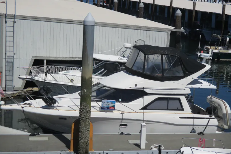 The Image of A 1995 Bayliner 3258 Avanti docked. It features a black canopy and is moored alongside other boats. - 6