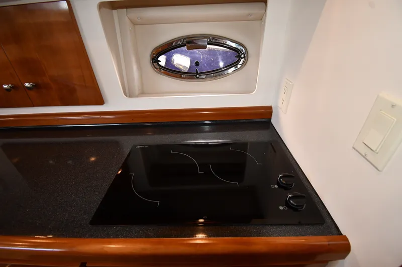 Slide: The Image of 2002 Carver 350 Mariner kitchen with sleek black cooktop and porthole window. - 44