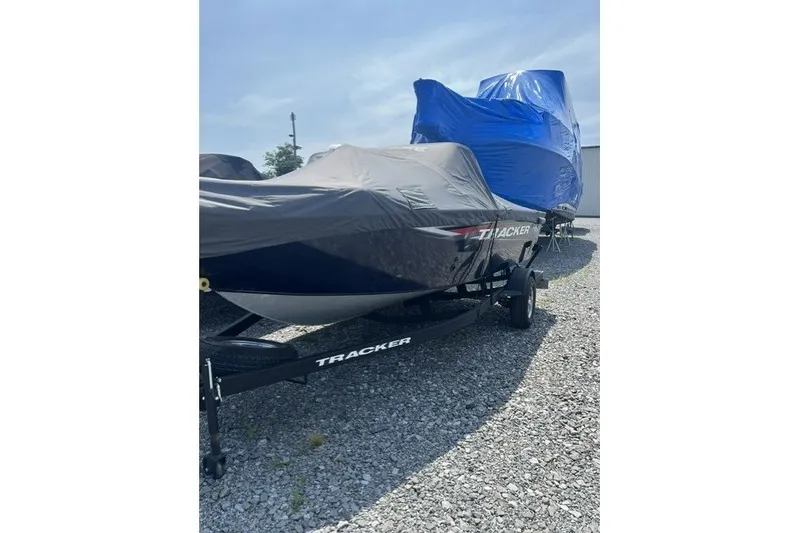 Slide: The Image of 2025 Tracker Pro Guide V-175 SC boat covered, parked on gravel lot. - 3