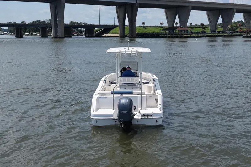 Slide: The Image of A white 2019 Robalo R222 Center Console boat cruising on a river under a bridge. - 3