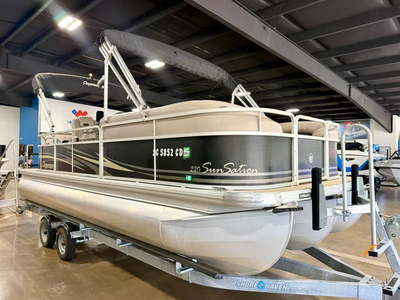 Slide: The Image of A 2011 Premier Sunsation 220 pontoon boat sits on a trailer in a showroom. - 3