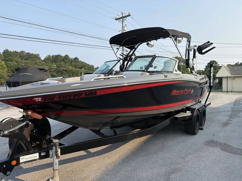 Slide: The Image of A black and red 2015 MasterCraft X30 boat on a trailer in a parking lot. - 4