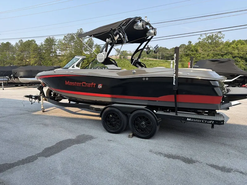 Slide: The Image of A black and red 2015 MasterCraft X30 boat on a trailer in a parking lot. - 5