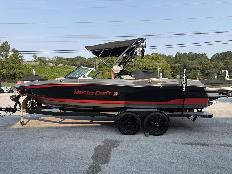 Slide: The Image of A black and red 2015 MasterCraft X30 boat on a trailer. It features a black canopy. - 6