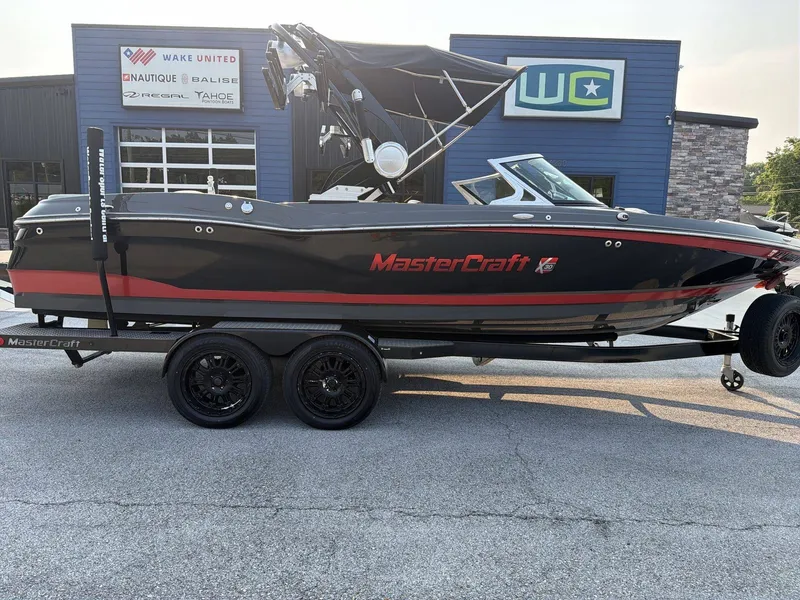 The Image of A black and red 2015 MasterCraft X30 boat on a trailer in front of a building. - 1