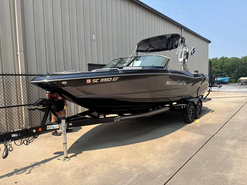 Slide: The Image of A 2019 MasterCraft XT25 boat on a trailer beside a building. - 3
