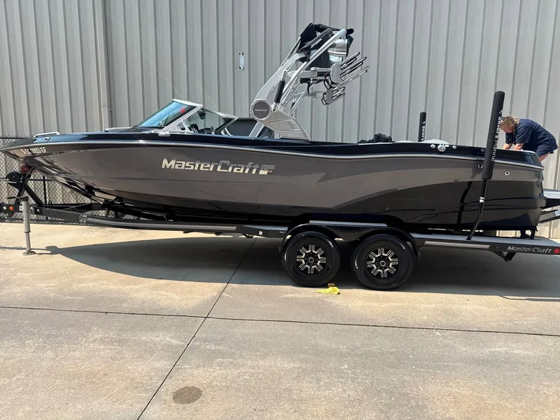 Slide: The Image of A 2019 MasterCraft XT25 boat on a trailer, featuring a sleek gray hull and a tower. - 2