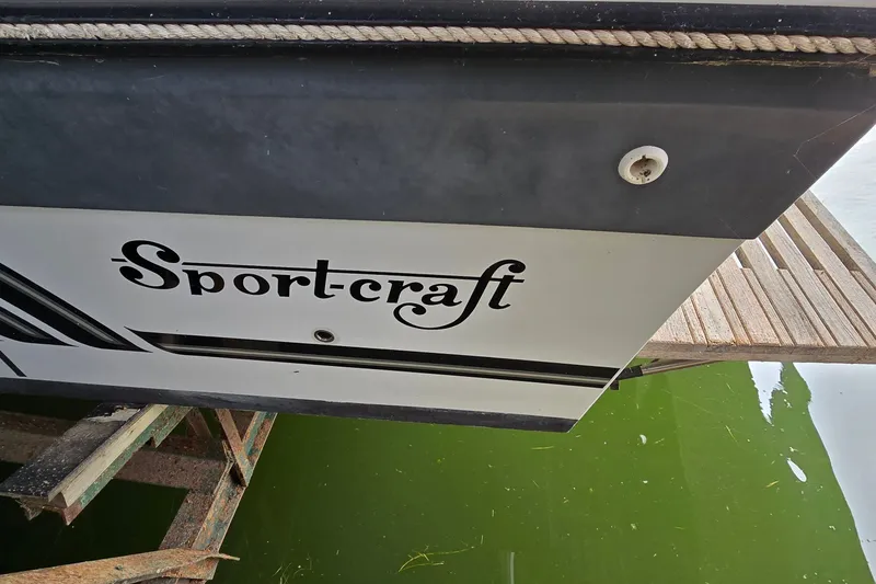 Slide: The Image of 1989 SportCraft 270 Fisherman boat with logo, docked on green water. - 8