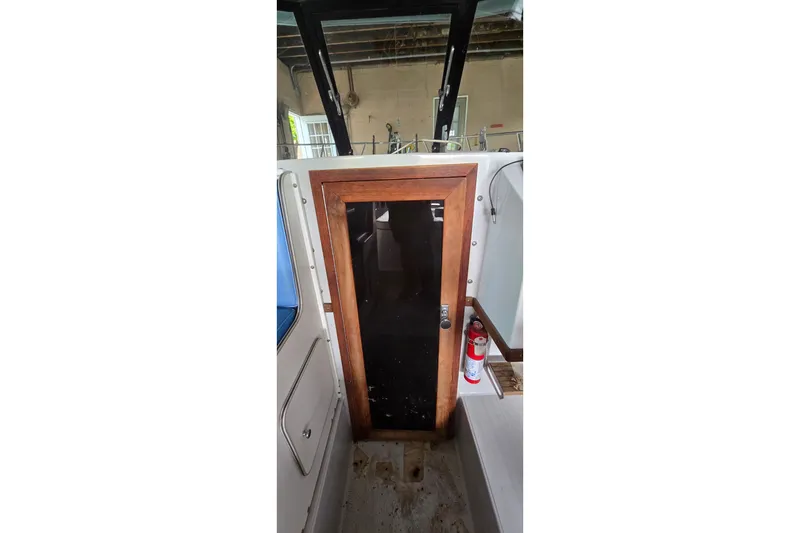 Slide: The Image of 1989 SportCraft 270 Fisherman cabin door with wooden frame and fire extinguisher nearby. - 19