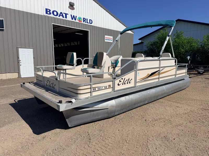 Slide: The Image of An Elete pontoon boat with a canopy sits on a gravel lot in front of a building. - 40