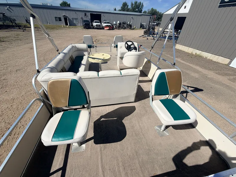 Slide: The Image of A pontoon boat with beige and green seats, a round table, and an open helm station. - 8
