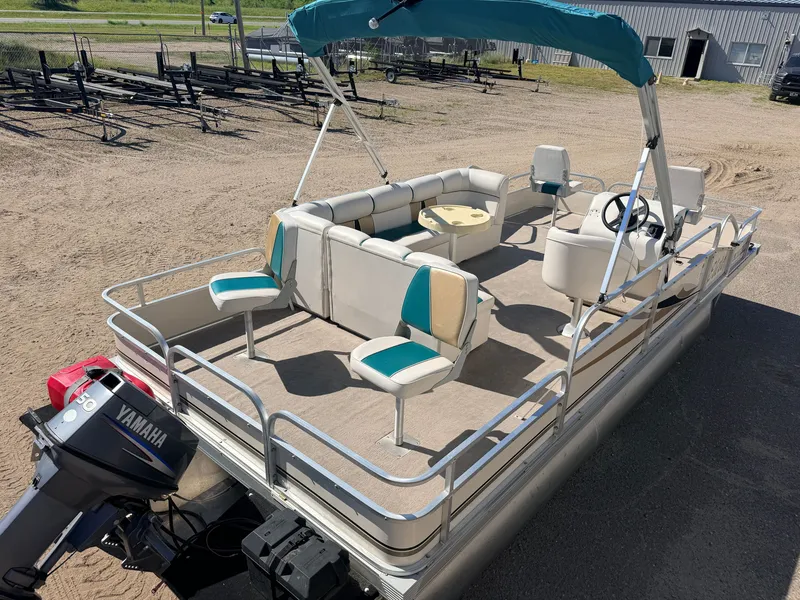 Slide: The Image of A pontoon boat with a blue canopy and 50HP Yamaha motor sits on sandy ground. - 7