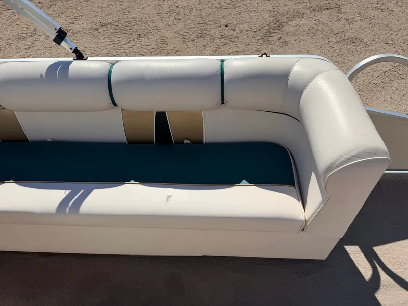 Slide: The Image of A white boat seat cushion with green accents, parked on sandy ground. - 24