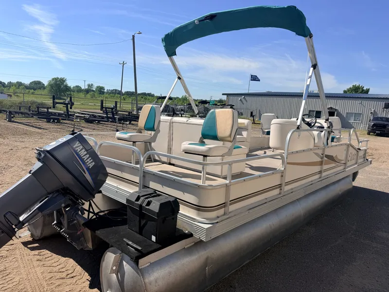 Slide: The Image of A pontoon boat with a blue sunshade and Yamaha outboard motor sits on dry land. - 48