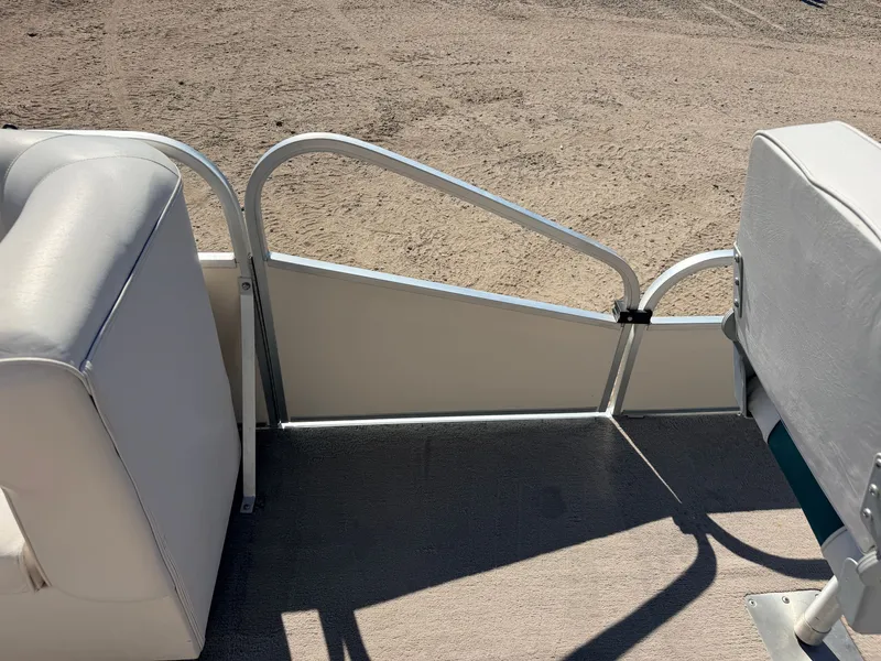 Slide: The Image of A boat with white upholstery and metal railing, parked on dry ground. - 13
