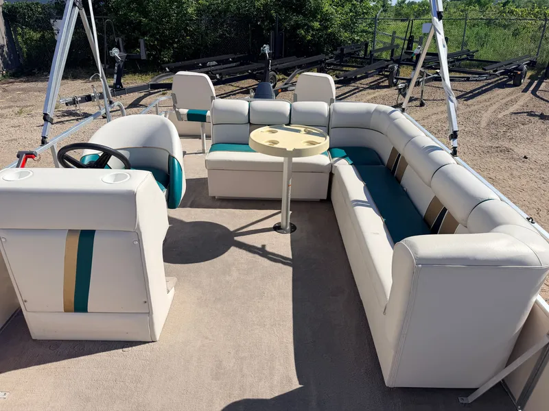Slide: The Image of A pontoon boat with beige and blue seating, a round table, and a steering wheel. - 5