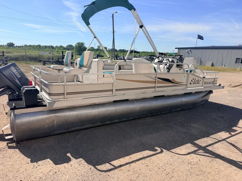 Slide: The Image of A pontoon boat with a blue sunshade and Yamaha motor is on dry land. - 50