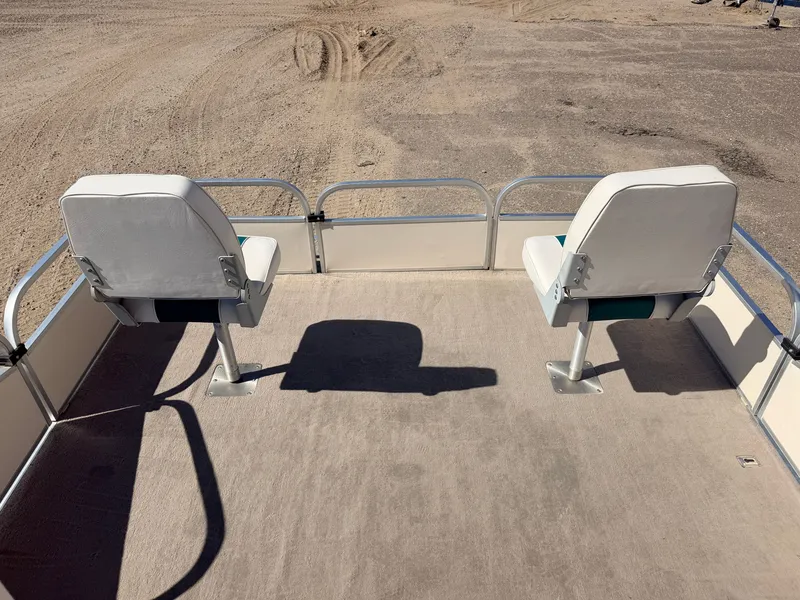 Slide: The Image of Two white seats on a carpeted boat deck, surrounded by metal railing, on dry land. - 3