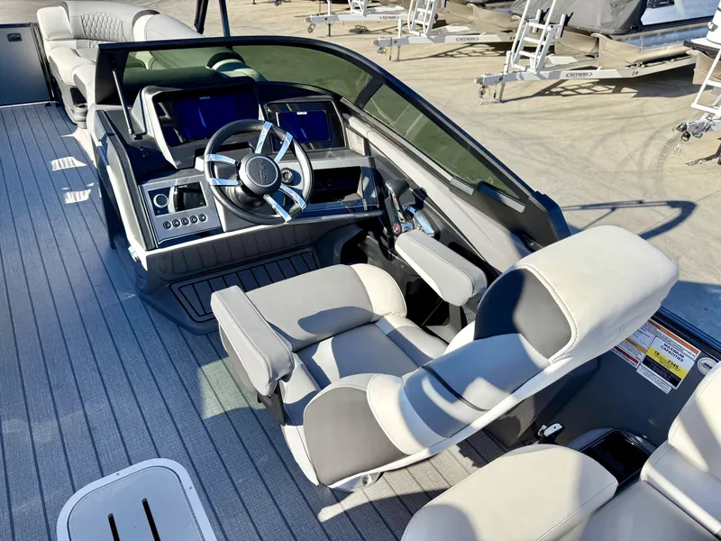 Slide: The Image of The image shows the cockpit of an Avalon Excalibur 27' LTD Quad Lounge with windshield. It features a modern helm with a sleek steering wheel and multiple screens. - 6