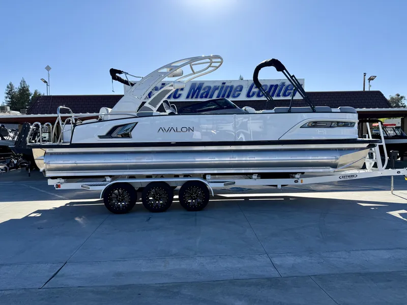 The Image of A luxurious Avalon Excalibur 27' LTD Quad Lounge boat with windshield, on a trailer. - 1