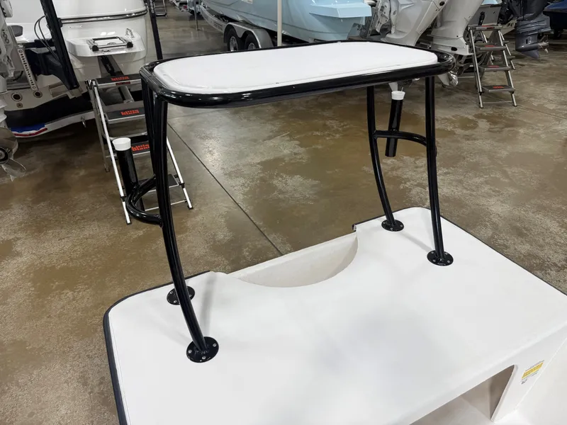 Slide: The Image of A white table with black legs on a boat, surrounded by other boats in a showroom. - 5