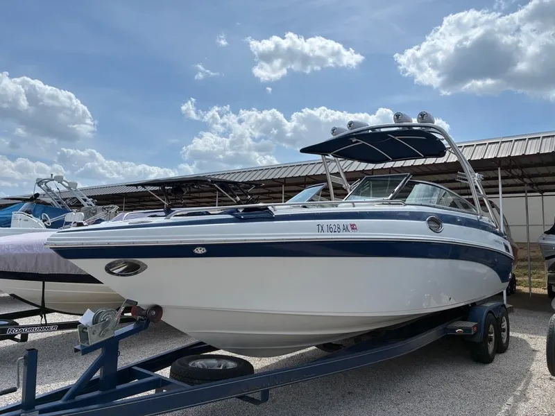 Slide: The Image of A 2007 Crownline 270BR on a trailer, featuring blue and white paint and a sunshade. - 11