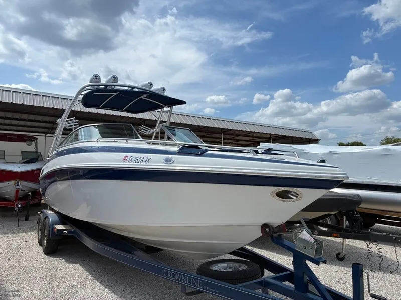 The Image of A 2007 Crownline 270BR on a trailer under a covered area. - 1