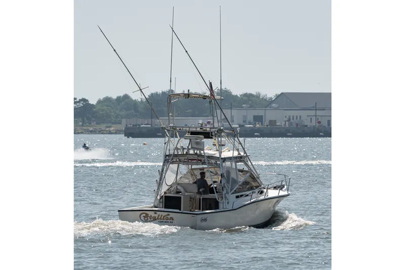 Slide: The Image of 2001 Carolina Classic 28 Express boat cruising on a sunny day near a harbor. - 20