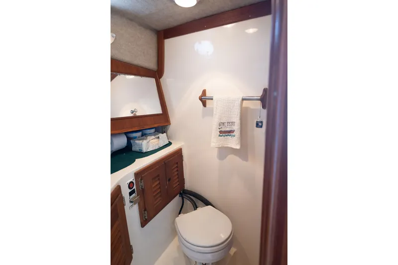 Slide: The Image of Compact bathroom in 2001 Carolina Classic 28 Express boat with wooden accents and towel rack. - 11