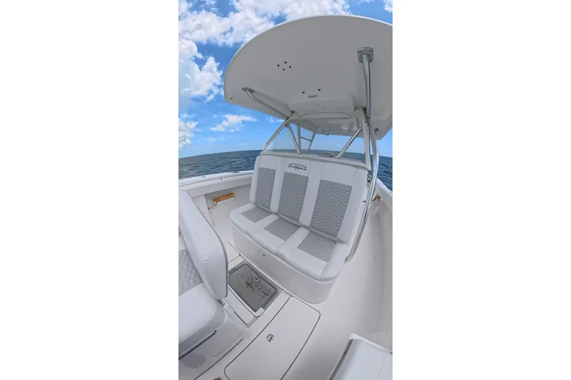 Slide: The Image of 2013 Invincible 42 Open Fisherman boat interior with cushioned seating, ocean backdrop, and blue sky. - 18