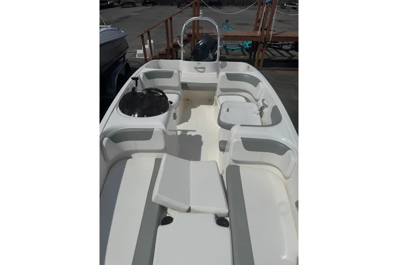 Slide: The Image of 2014 Bayliner 160 Element boat interior with seating and steering wheel, docked outdoors. - 3