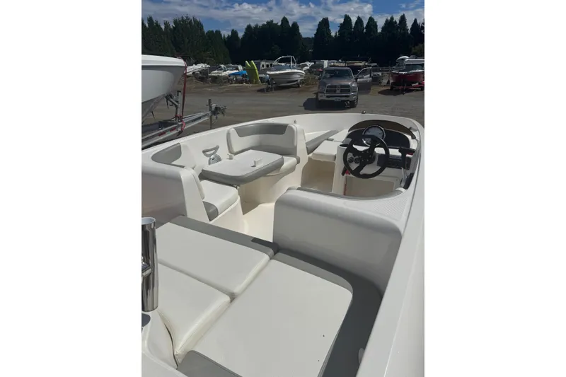 Slide: The Image of 2014 Bayliner 160 Element boat interior with seating and steering wheel, parked outdoors. - 4