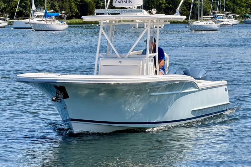 Slide: The Image of A 2014 Buddy Davis 28 Center Console boat cruising on calm water. Other boats are visible in the background. - 2
