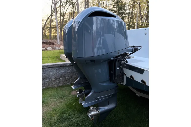 Slide: The Image of Two outboard motors on a boat standing on grass, with trees in the background. - 31