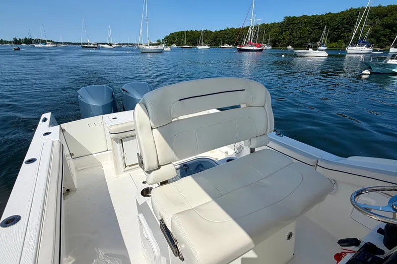 Slide: The Image of A 2014 Buddy Davis 28 Center Console boat on calm water with several sailboats in the background. - 13