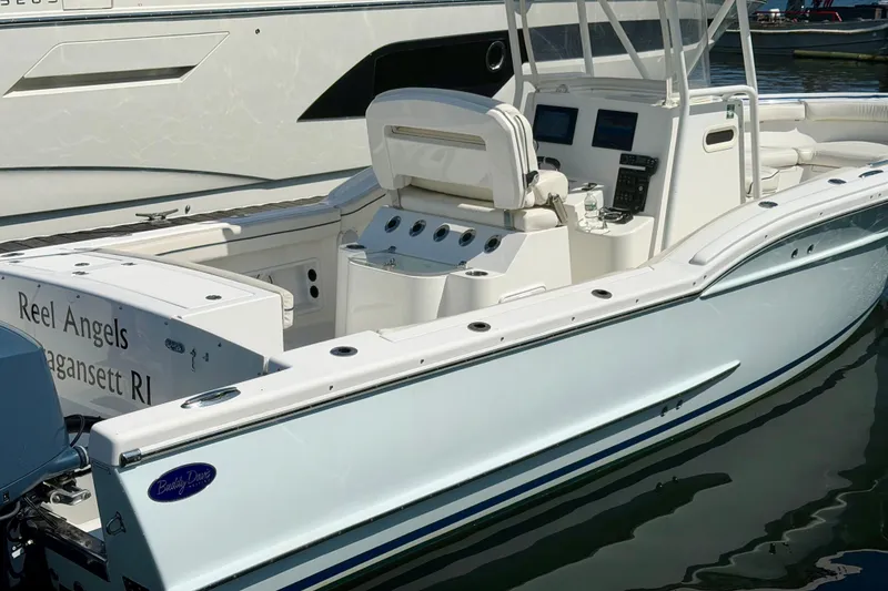 Slide: The Image of A white 2014 Buddy Davis 28 Center Console boat is docked. It features an open deck and modern controls. - 26