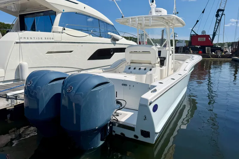Slide: The Image of A 2014 Buddy Davis 28 Center Console boat with twin outboard engines, docked beside a larger boat. - 23