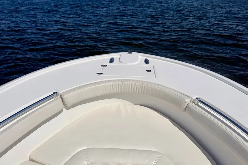 Slide: The Image of The front of a white boat with cushioned seating and stainless steel railings on calm water. - 7