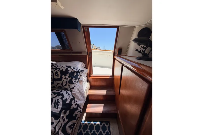Slide: The Image of Interior of 1990 Californian 48 Motor Yacht with wooden stairs and patterned bedding. - 105