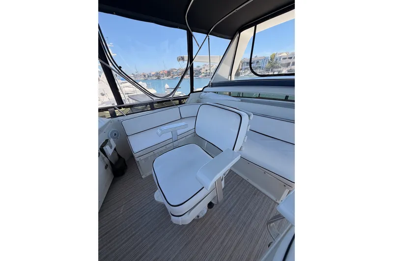 Slide: The Image of Interior of 1990 Californian 48 Motor Yacht with white seating and marina view. - 49