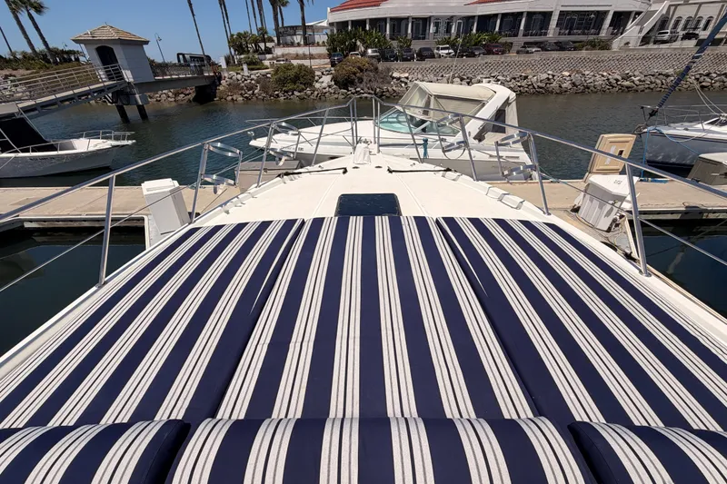 Slide: The Image of 1990 Californian 48 Motor Yacht with striped deck cushions docked at marina. - 22