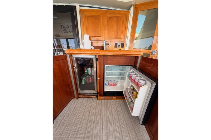 Slide: The Image of Interior of 1990 Californian 48 Motor Yacht with open mini fridge and wooden cabinetry. - 18