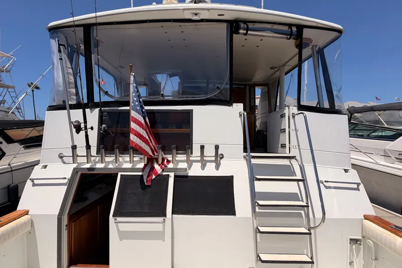 Slide: The Image of 1990 Californian 48 Motor Yacht with American flag, docked under clear blue sky. - 9