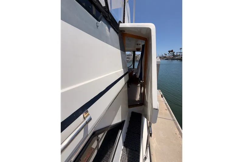Slide: The Image of 1990 Californian 48 Motor Yacht side view with open cabin door, docked by calm water. - 25